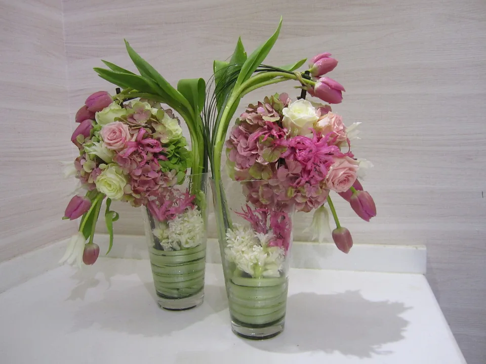 Dos arreglos de hortensias y tulipanes en vasos de cristal